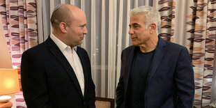 Jair Lapid unterhält sich in einem Raum mit Gardinen Naftali Bennett