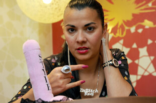 Einen Dildo vor sich auf den Tisch platziert posiert Lady Bitch Ray 2012: Anlass ist eine Buchveröffentlichung.