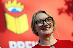 Porträt der Autorin Autorin Kristine Bilkau, sie trägt eine Brille, einen roten Pullover und lächelt