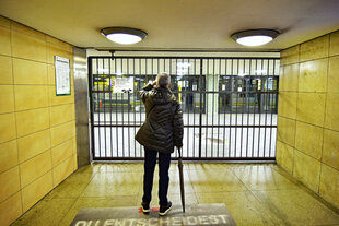 Eine Person steht vor einer vergitterten U-Bahn-Station