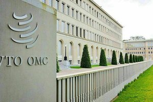 Ausenaufnahme des WTO Hauptgebäudes mit ordentlich gestutzten Bäumchen, einer hellen Fassade und grünem Rasen