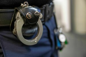 Handschellen hängen am Gürtel eines Polizisten
