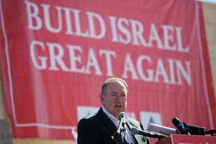 Mike Huckabee vor einem Plakt mit der Aufschrift "Build Israel Great Again"