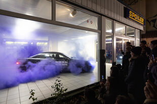 Foto von einer Kunstperformance, bei der ein Auto auf der Stelle fährt, bis die Reifen abgefahren sind