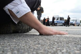 Eine Hand,festgeklebt am Aspahlt.